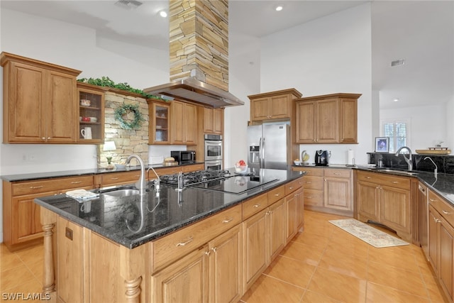 kitchen featuring dark stone countertops, sink, stainless steel appliances, and a kitchen island with sink