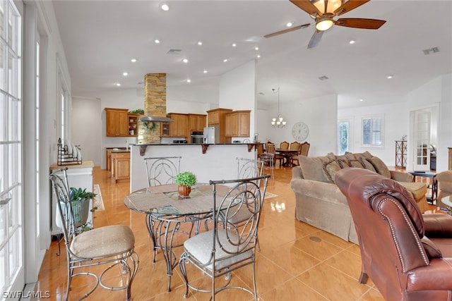 tiled dining room with ceiling fan with notable chandelier and vaulted ceiling