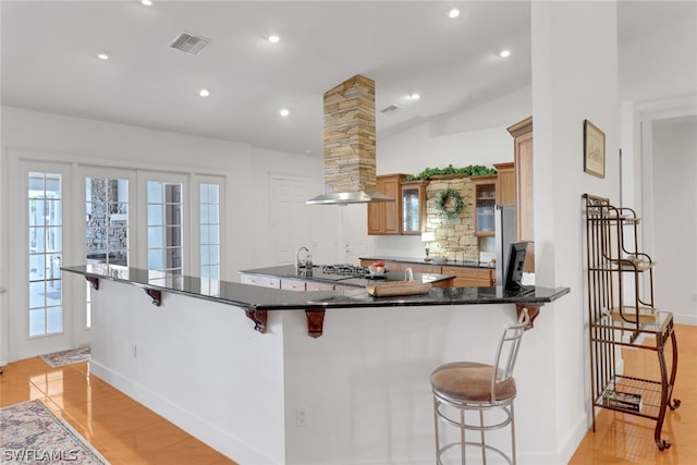 kitchen with a kitchen breakfast bar, light wood-type flooring, kitchen peninsula, and ornate columns