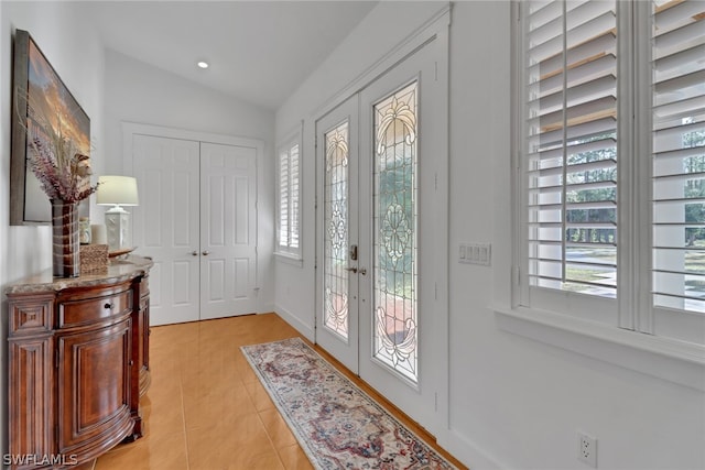 doorway to outside with light tile patterned floors, lofted ceiling, a wealth of natural light, and french doors