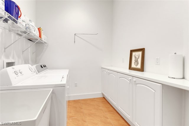 laundry area featuring light tile patterned flooring, cabinets, and washing machine and clothes dryer