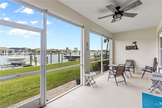 sunroom featuring ceiling fan, a healthy amount of sunlight, and a water view