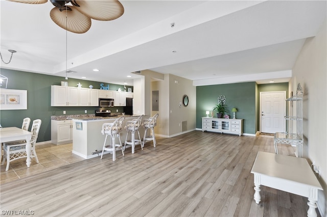 kitchen with light tile flooring, a breakfast bar, appliances with stainless steel finishes, white cabinetry, and hanging light fixtures