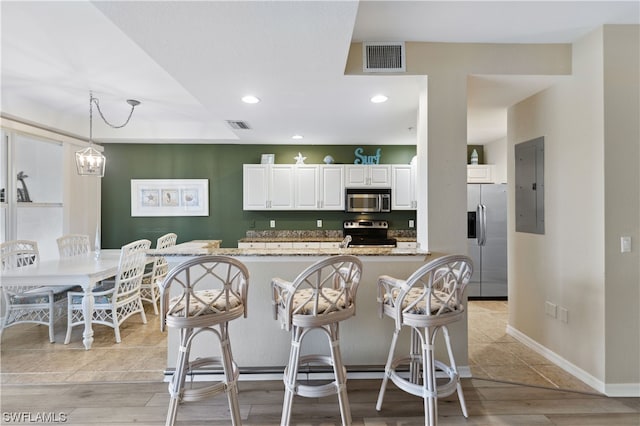 kitchen featuring white cabinets, light stone counters, light wood-type flooring, and stainless steel appliances