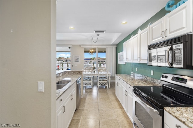 kitchen with light tile floors, light stone counters, a raised ceiling, stainless steel appliances, and white cabinetry