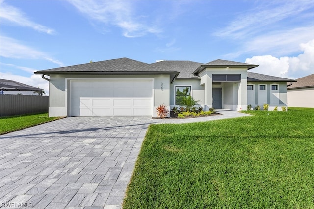 prairie-style house with a garage, fence, a front lawn, and decorative driveway