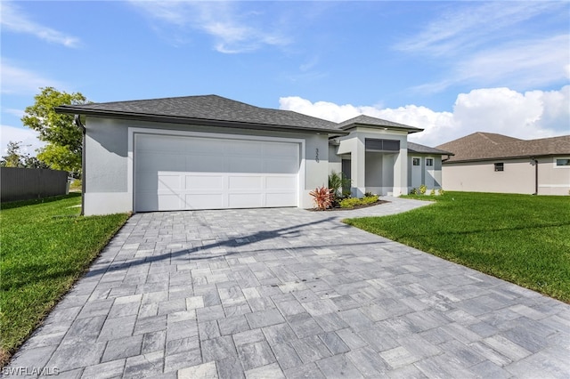 prairie-style home with a garage, decorative driveway, a front yard, and stucco siding