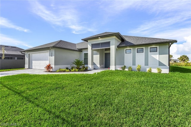 prairie-style house featuring driveway, a front lawn, an attached garage, and stucco siding