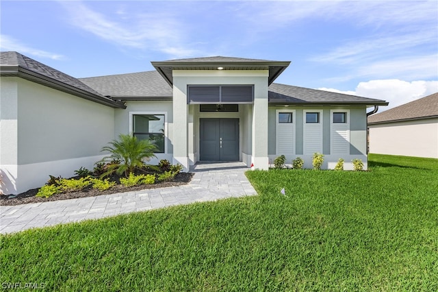 property entrance with a shingled roof, a lawn, and stucco siding