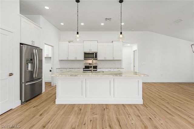 kitchen featuring light stone counters, a center island with sink, stainless steel appliances, hanging light fixtures, and white cabinetry