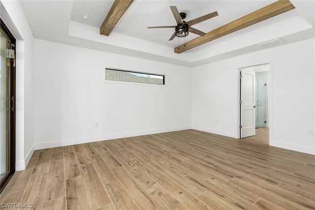 empty room with light wood finished floors, baseboards, a raised ceiling, and beamed ceiling