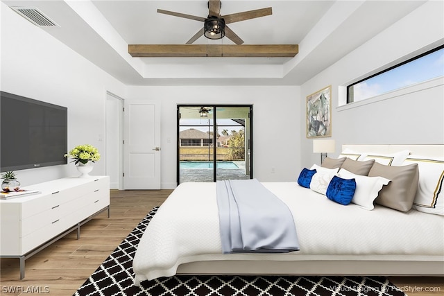 bedroom featuring visible vents, a ceiling fan, wood finished floors, access to outside, and a tray ceiling