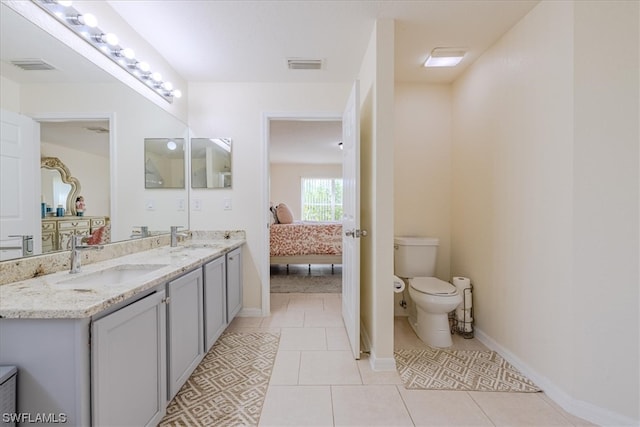 bathroom with toilet, vanity, and tile patterned flooring