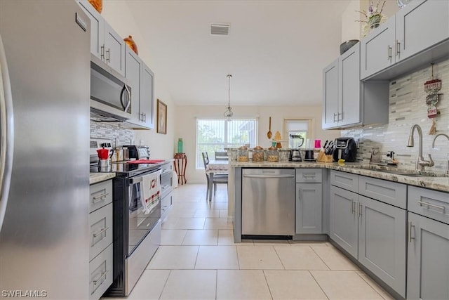 kitchen with appliances with stainless steel finishes, sink, gray cabinetry, decorative light fixtures, and kitchen peninsula