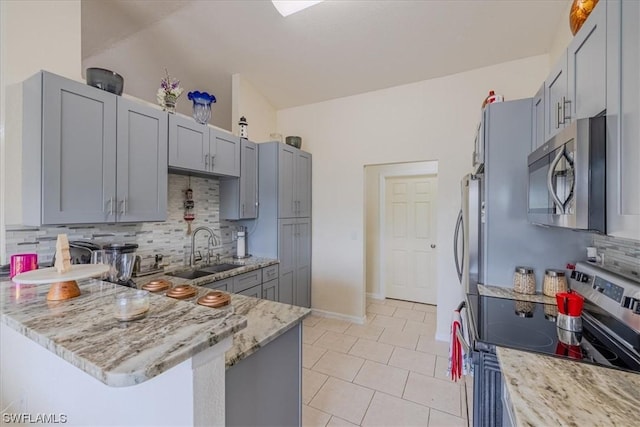 kitchen with appliances with stainless steel finishes, tasteful backsplash, light stone counters, sink, and kitchen peninsula