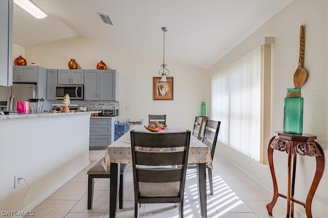 tiled dining room with vaulted ceiling