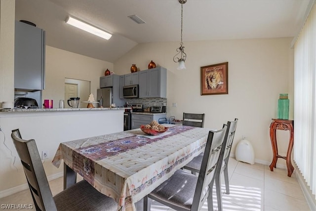 tiled dining area featuring vaulted ceiling