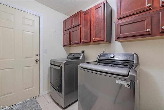 laundry room with cabinets, washer and dryer, and light tile patterned floors