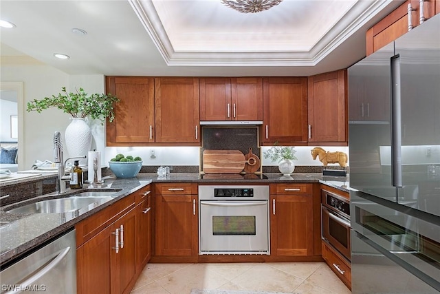 kitchen featuring appliances with stainless steel finishes, a tray ceiling, and dark stone counters