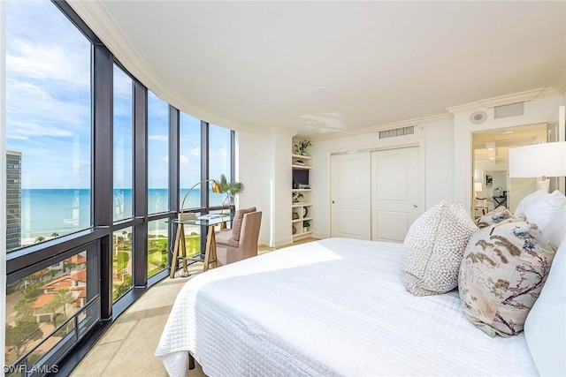 bedroom featuring floor to ceiling windows, a water view, crown molding, and a closet