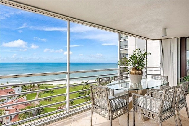 sunroom featuring plenty of natural light, a water view, and a beach view