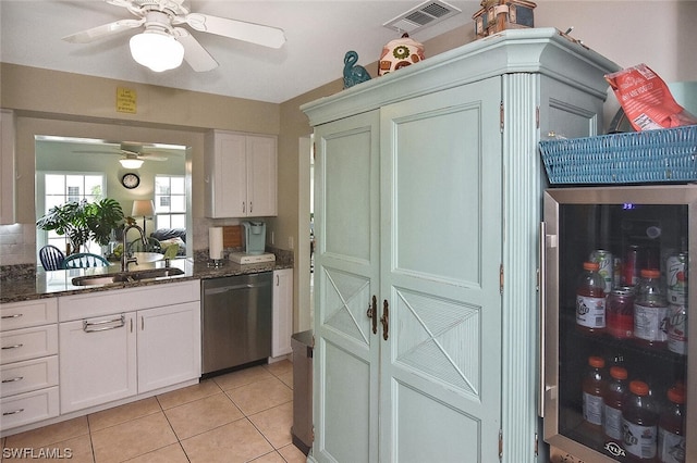 kitchen with dishwasher, dark stone counters, white cabinets, sink, and light tile patterned floors