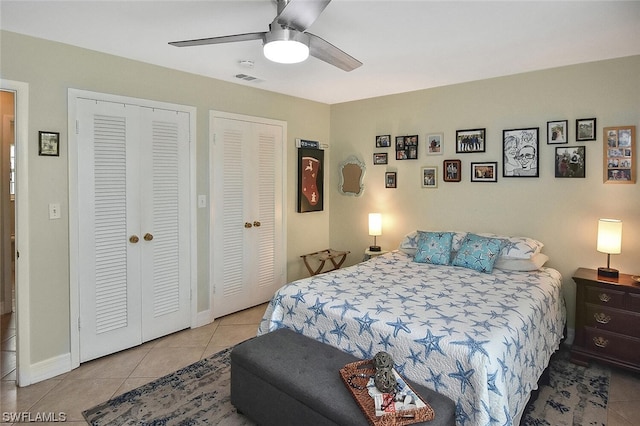 tiled bedroom with ceiling fan and multiple closets