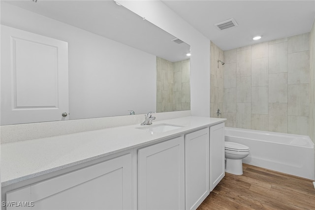 full bathroom with tiled shower / bath, vanity, toilet, and hardwood / wood-style flooring