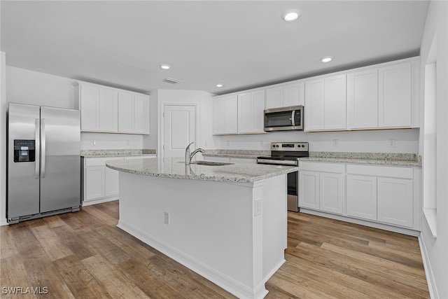 kitchen with appliances with stainless steel finishes, white cabinetry, light hardwood / wood-style flooring, and sink