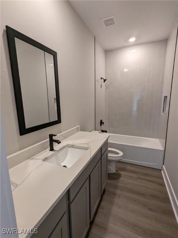 full bathroom with tiled shower / bath, wood-type flooring, toilet, and vanity