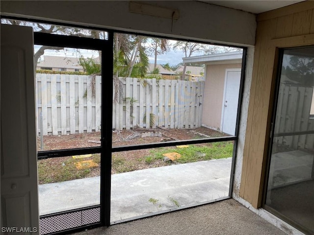 doorway to outside featuring carpet floors and wood walls