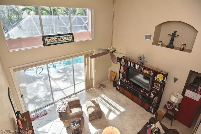 living room featuring ceiling fan, light tile patterned floors, and a high ceiling