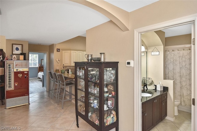 kitchen featuring light tile patterned floors, dark brown cabinets, and sink