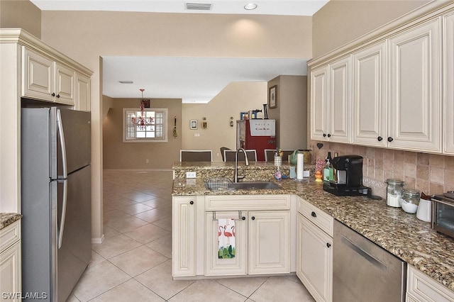 kitchen with sink, dark stone countertops, appliances with stainless steel finishes, tasteful backsplash, and kitchen peninsula