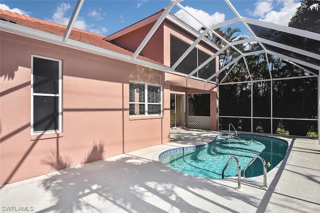 view of pool with glass enclosure and a patio