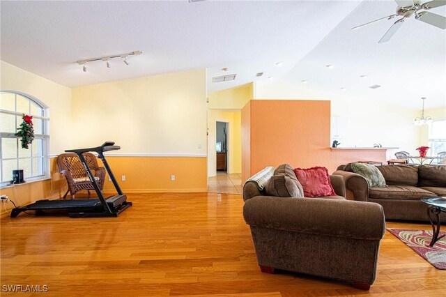 exercise area featuring ceiling fan, light wood-type flooring, and vaulted ceiling