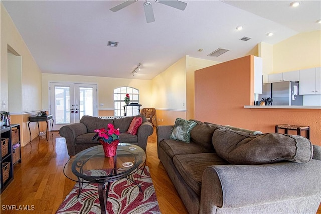 living room with ceiling fan, french doors, wood-type flooring, and vaulted ceiling