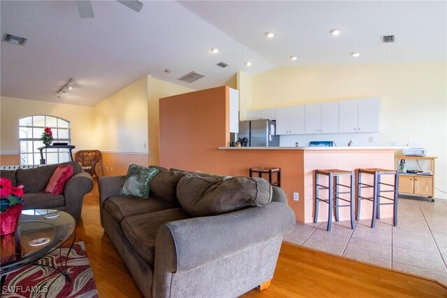 living room featuring ceiling fan, light hardwood / wood-style floors, and lofted ceiling