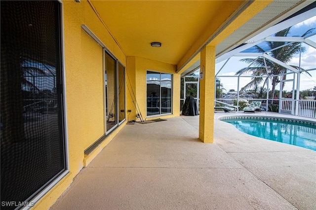 view of swimming pool featuring a patio and glass enclosure