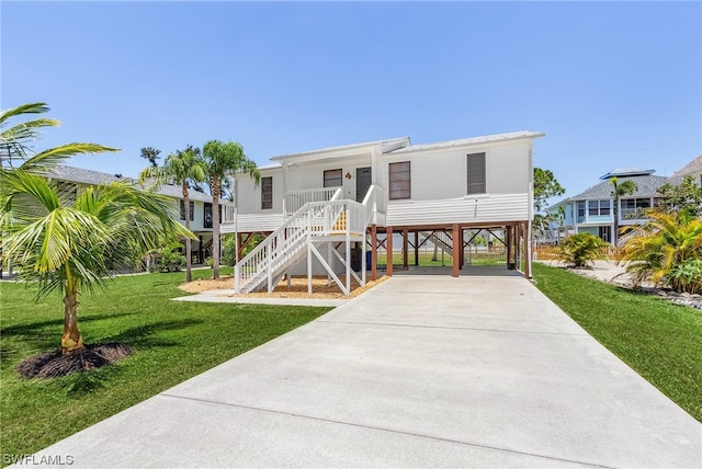 raised beach house featuring a front lawn and a carport