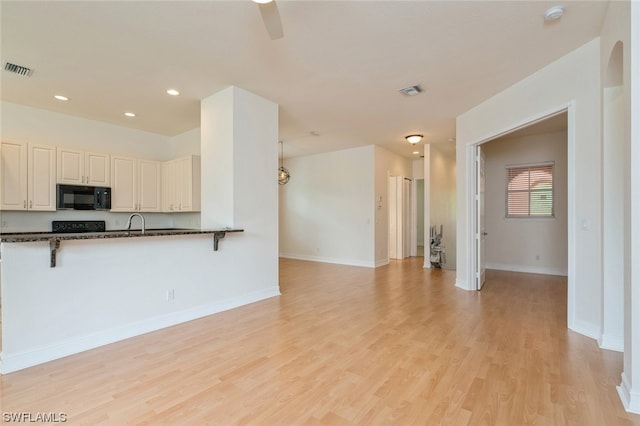 kitchen featuring ceiling fan, sink, dark stone counters, range, and light wood-type flooring