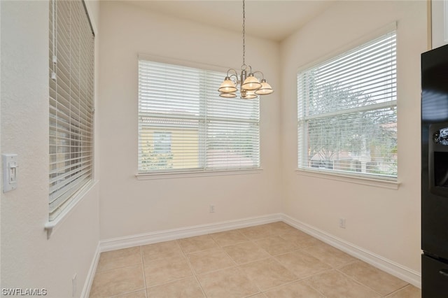 tiled empty room featuring an inviting chandelier and a wealth of natural light