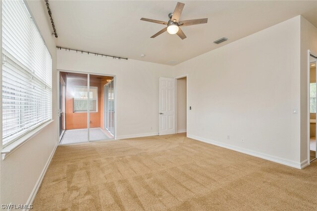 unfurnished room featuring plenty of natural light, ceiling fan, and light colored carpet