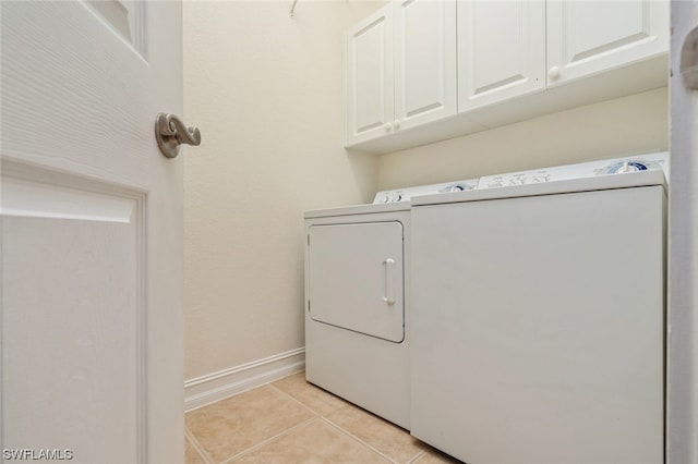 laundry room with cabinets, washer and dryer, and light tile flooring