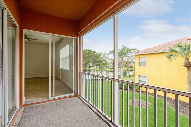 unfurnished sunroom with ceiling fan and a water view