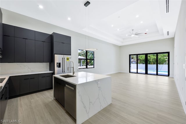 kitchen featuring sink, decorative light fixtures, a raised ceiling, stainless steel appliances, and a large island