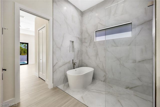 bathroom featuring a bath, hardwood / wood-style floors, and tile walls