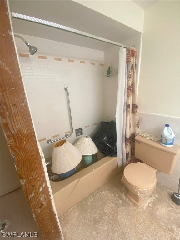 bathroom with concrete floors, shower / bath combination with curtain, and toilet