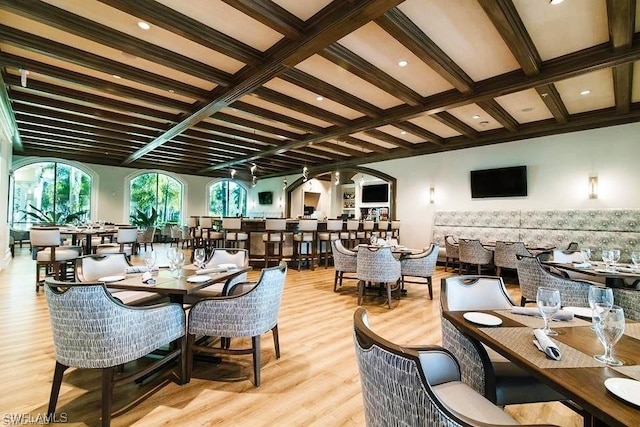 dining area with beamed ceiling, a wealth of natural light, and light hardwood / wood-style floors