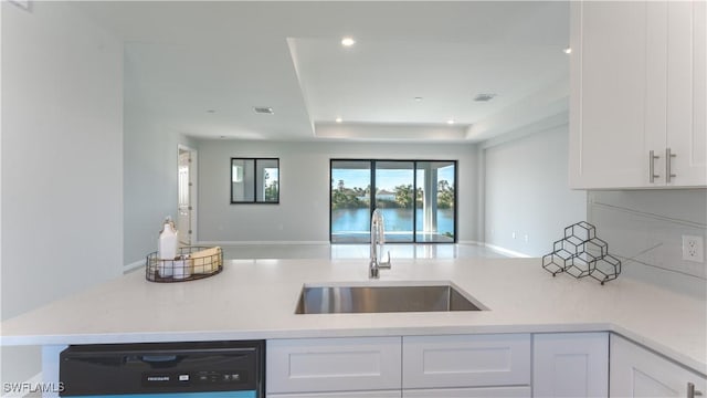 kitchen featuring sink, black dishwasher, white cabinets, and a raised ceiling